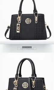 Detail of black faux crocodile leather handbag with golden hardware and round emblem