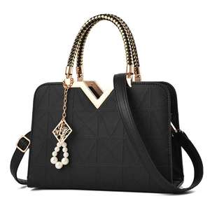 Black geometric quilted handbag with woven handles and gold V-shaped metal accent
