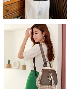 Detail of a brown quilted backpack with a cute rabbit charm and metal zipper