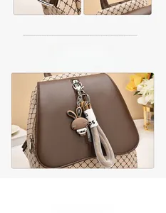 Detail of brown faux leather backpack featuring a cute rabbit charm and woven letter strap