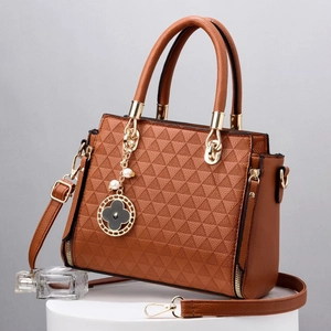 Detail of brown handbag with geometric triangle embossing and golden clover charm