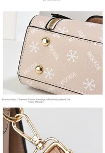 Detail view of beige handbag with gold bottom studs and metal logo hardware