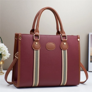 Deep red tote bag with brown handles and striped ribbon detail, 45-degree front view