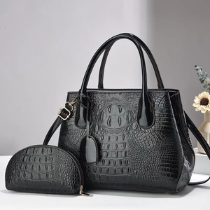 Detail of black crocodile texture tote bag and matching coin purse with gold hardware