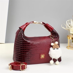 Dettaglio della mini borsa bordeaux con trama a coccodrillo, fibbie dorate e ciondolo