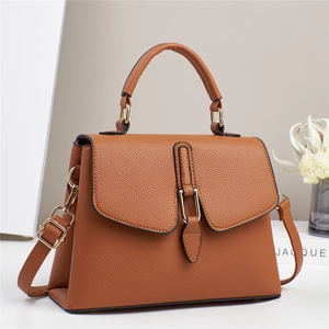 Detail of a brown lychee pattern leather handbag with golden metal buckle and top handle