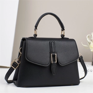 Close-up of black lychee grain leather handbag with gold hardware and curved handle
