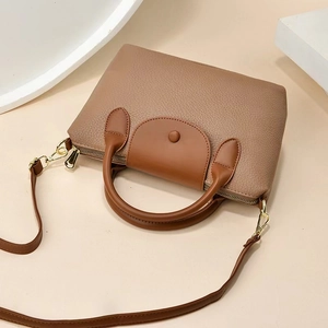 Top view of brown lychee texture leather handbag with gold zipper and round handles