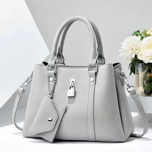 Detail of light grey pebbled leather handbag with metal padlock and mini envelope pouch