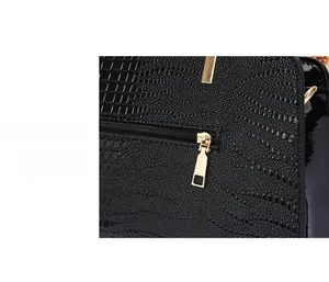 Detail of black faux crocodile skin texture and premium smooth golden zipper on handbag