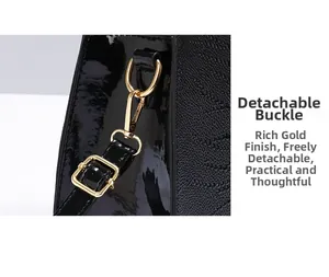Detail of black faux crocodile leather handbag with gold metal clasp and adjustable strap