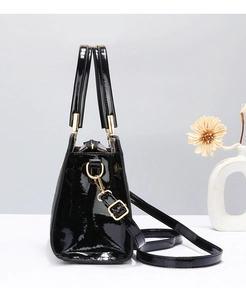 Side view of black patent leather tote bag with glossy finish and gold metal hardware