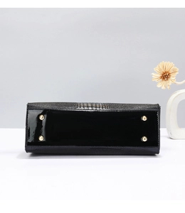 Detail view of glossy crocodile pattern handbag base with four protective gold metal feet