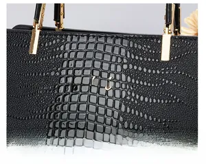 Detailed view of black crocodile pattern leather with gold metal Danbaoly logo and hardware