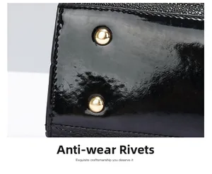 Detail view of gold anti-wear rivets on black patent leather handbag bottom