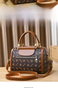 Detail view of monogram Boston bag with brown leather handles and woven shoulder strap