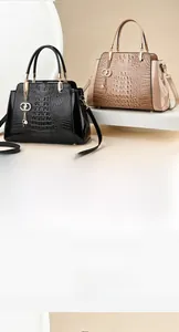 Detail of crocodile embossed handbags in black and apricot with metallic letter pendants