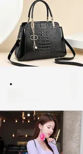 Close-up of black crocodile embossed handbag with glossy finish and gold metal handle