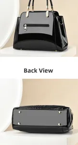 Detail view of black patent leather handbag featuring back zip pocket and gold metal feet