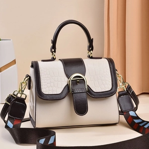 Detail of crocodile embossed flap and gold buckle on stylish two-tone crossbody bag