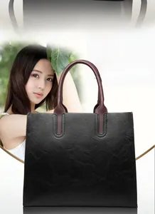 Close-up of black textured faux leather tote with brown handles and FASHION detail