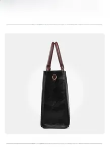 Detail view of black faux leather tote with brown handles and gold D-ring hardware