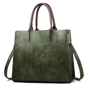 Vintage dark green faux leather tote bag with brown handles and gold hardware in studio light
