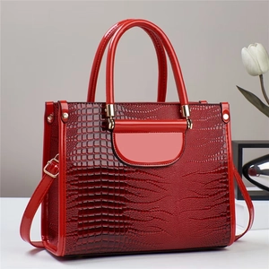 Détail d'un sac à main rouge en cuir verni gaufré croco avec finitions dorées chic