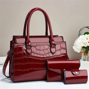 Close-up of three-piece dark red patent leather bag set with crocodile texture finish