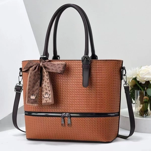 Detailed texture of brown woven tote bag with decorative silk scarf and metal zippers