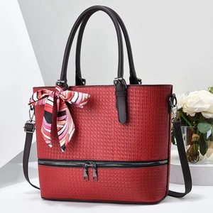 Detail of red woven bucket tote bag with black handles and colorful printed silk scarf bow