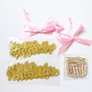 Close-up of golden glitter birthday banner letters with pink bows and wooden photo clips