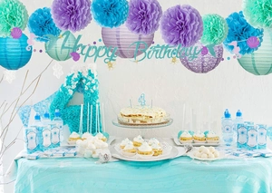Close-up of Happy Birthday banner with paper lanterns and pom-poms in ocean theme colors