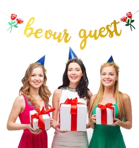Close-up of gold glitter Be Our Guest party banner with decorative red roses