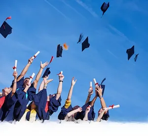 Outdoor graduation scene with black caps and diplomas under a clear blue sky