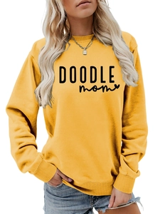 Close-up of DOODLE MOM text print on a mustard yellow casual long-sleeve crewneck sweatshirt