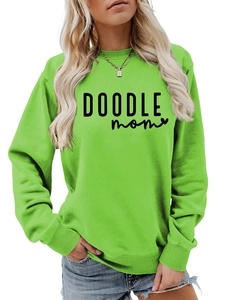 Close-up of DOODLE MOM text and heart print on long-sleeved green crewneck sweatshirt