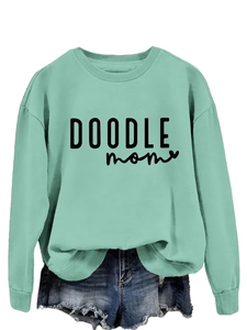 Detail of mint green sweatshirt featuring ribbed cuffs and DOODLE mom graphic print
