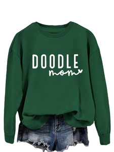Detail of dark green sweatshirt with white DOODLE MOM text and frayed denim shorts