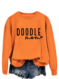 Detail of orange crewneck sweatshirt with black DOODLE MOM text and frayed denim shorts