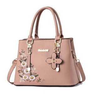 Detail of pink faux leather handbag with white daisy embroidery and gold floral charm