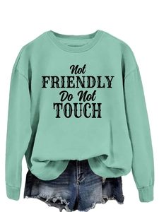 Detail of mint green sweatshirt with Not Friendly Do Not Touch text and frayed denim shorts