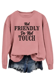Flat lay of pink crewneck sweatshirt with Not Friendly slogan and denim shorts