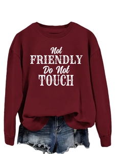 Detail of red crewneck sweatshirt with Not FRIENDLY Do Not TOUCH text and ribbed cuffs