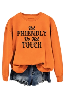 Close-up of orange sweatshirt with black 'Not FRIENDLY Do Not TOUCH' slogan print