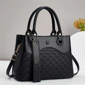 Close-up of black handbag detailing smooth leather, woven texture, and metal rivets