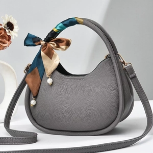 Detail of grey lychee leather handbag featuring a silk scarf handle and pearl pendant
