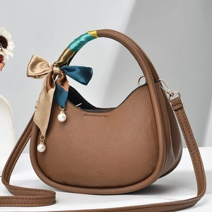 Close-up of brown litchi-grain PU leather semi-circle bag with silk scarf on handle