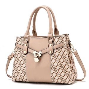 Close-up of golden padlock pendant and monogram texture on a beige fashion handbag