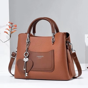 Chic tan pebbled leather handbag with contrast pocket and silver heart charm pendant